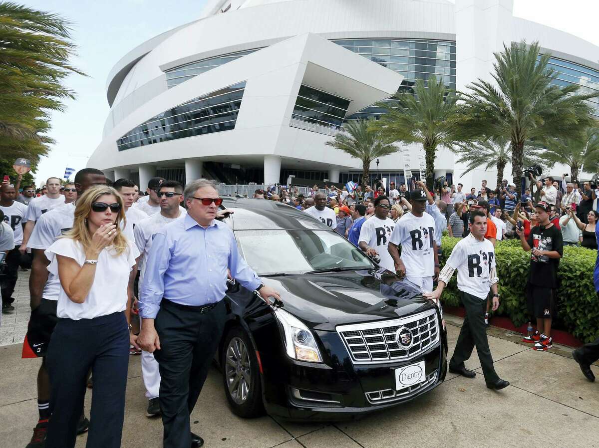 Miami Marlins owner and CEO Jeffrey Loria, second left, and Marlins president David Samson, right, lead players and staff as they escort a hearse carrying the body of pitcher Jose Fernandez as it leaves Marlins Park stadium Wednesday in Miami. Fernandez was killed in a weekend boat crash along with two friends.