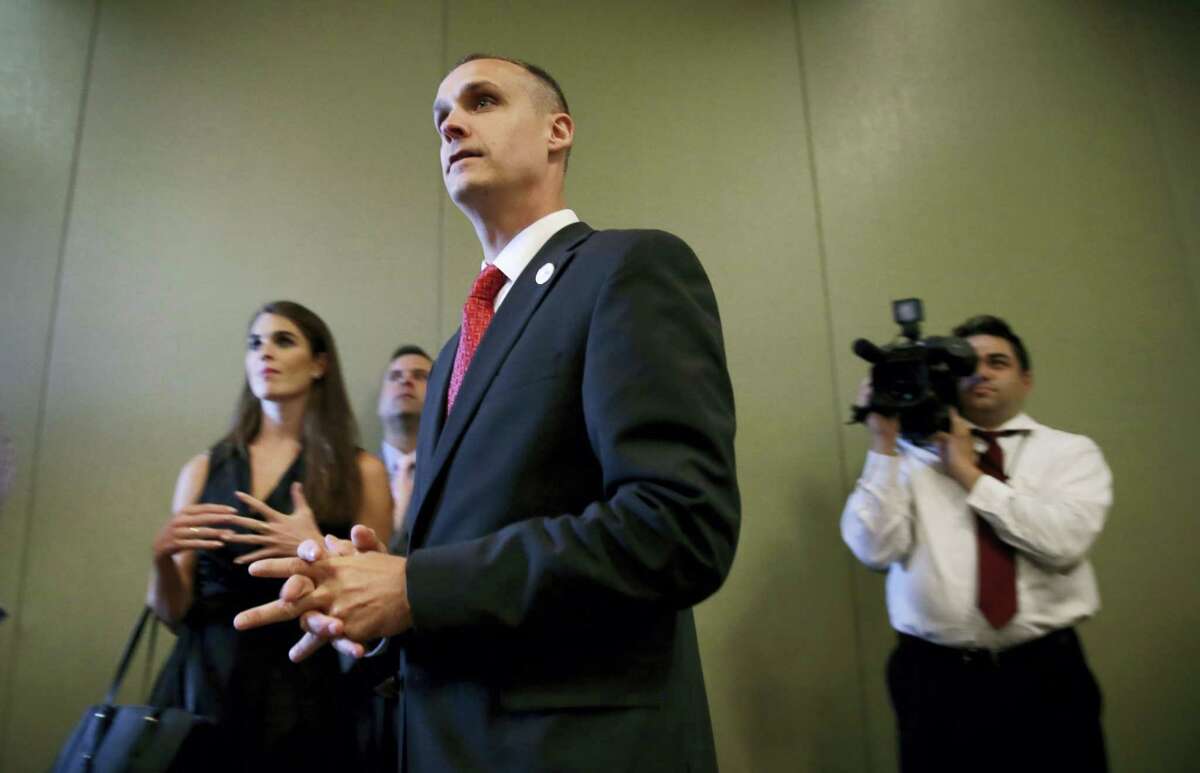 In this photo taken Aug. 25, 2015, Republican presidential candidate Donald Trump’s campaign manager Corey Lewandowski watches as Trump speaks in Dubuque, Iowa. Florida police have charged Lewandowski with simple battery in connection with an incident earlier in the month involving a reporter.