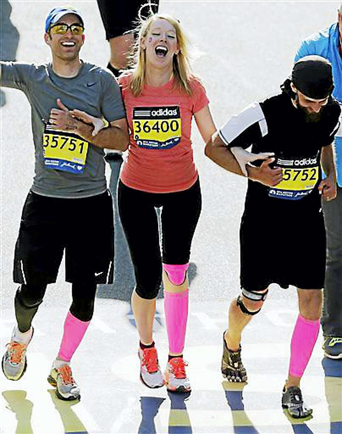 In this April 21, 2014, file photo, Timothy Haslet, left, and David Haslet, right, celebrate with their sister Adrianne Haslet-Davis at the finish line of the 118th Boston Marathon, after she completed a short distance of the course in Boston. Haslet-Davis said she is training to run the entire Boston Marathon on Monday, April 18, 2016. Haslet-Davis lost her left leg below the knee in the April 2013 bombing attacks, which killed three people and wounded more than 260 others.