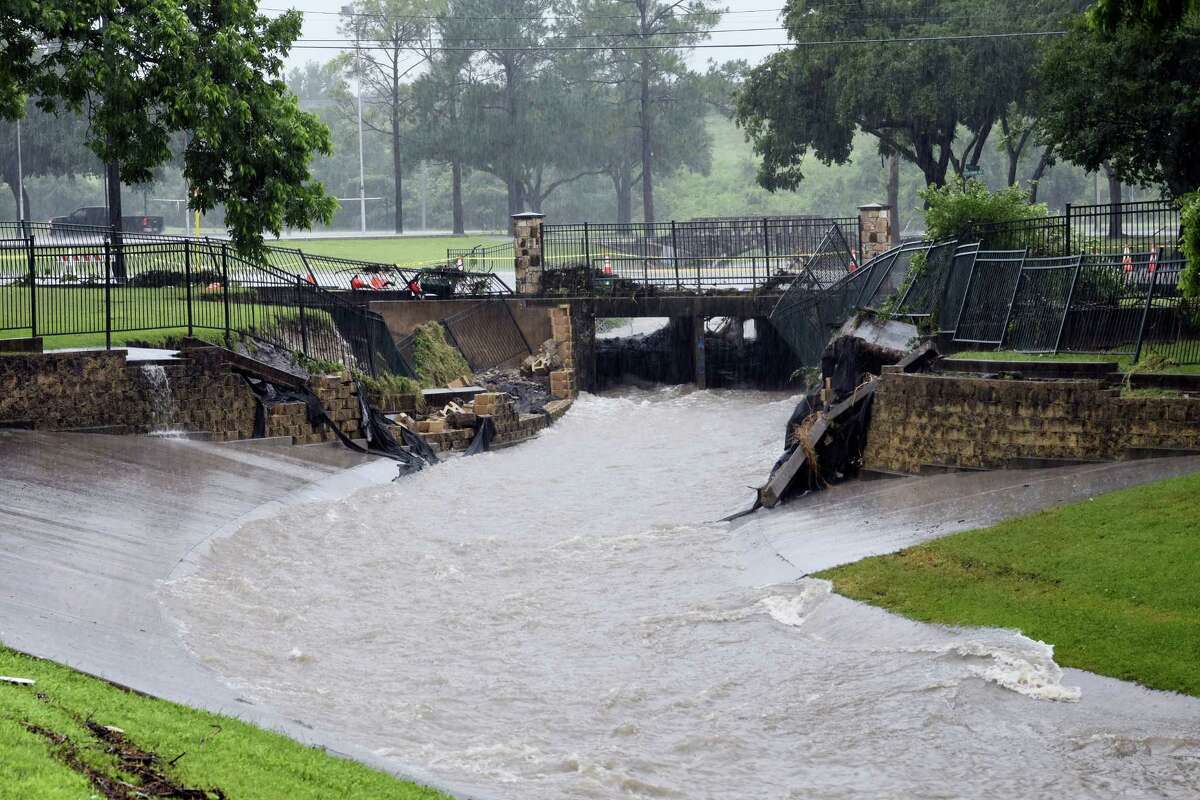 Water rushes down a canal under the washed out bridge at North Park Street in Fireman’s Park as heavy rain falls, Friday, May 27, 2016, in Brenham, Texas.