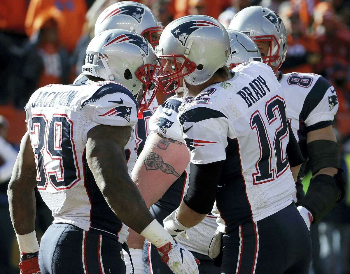 New England Patriots running back Steven Jackson (39) is congratulated by Tom Brady after scoring on a touchdown on a one-yard run during the first half Sunday.