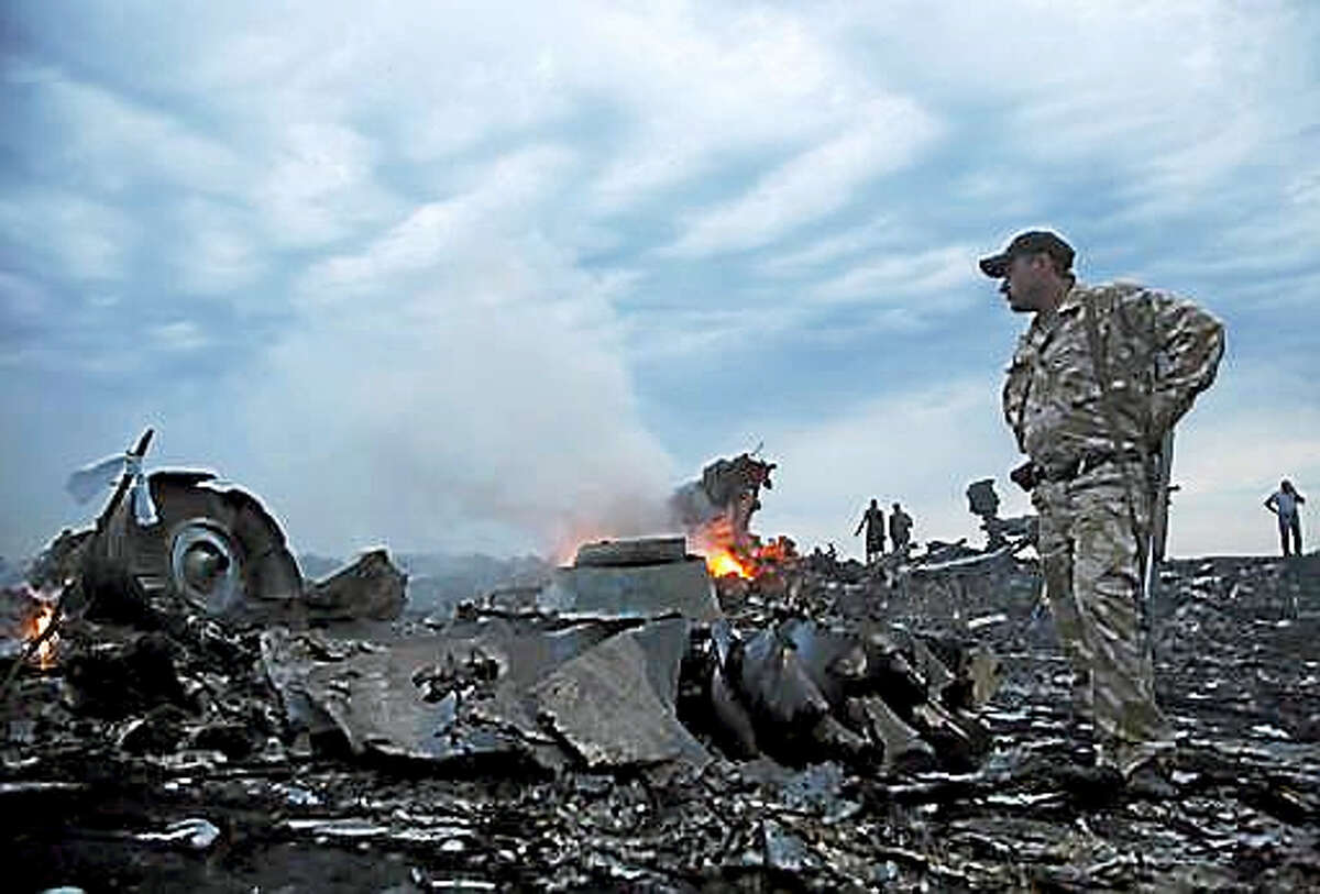 In this Thursday, July 17, 2014, file photo, people walk amongst the debris, at the crash site of a passenger plane near the village of Grabovo, Ukraine. Relatives of victims of the shooting-down of a Malaysia Airlines jetliner over Ukraine more than two years ago were gathering Wednesday, Sept. 28, 2016, to learn the preliminary results of a Dutch-led criminal probe of the disaster that claimed 298 lives.