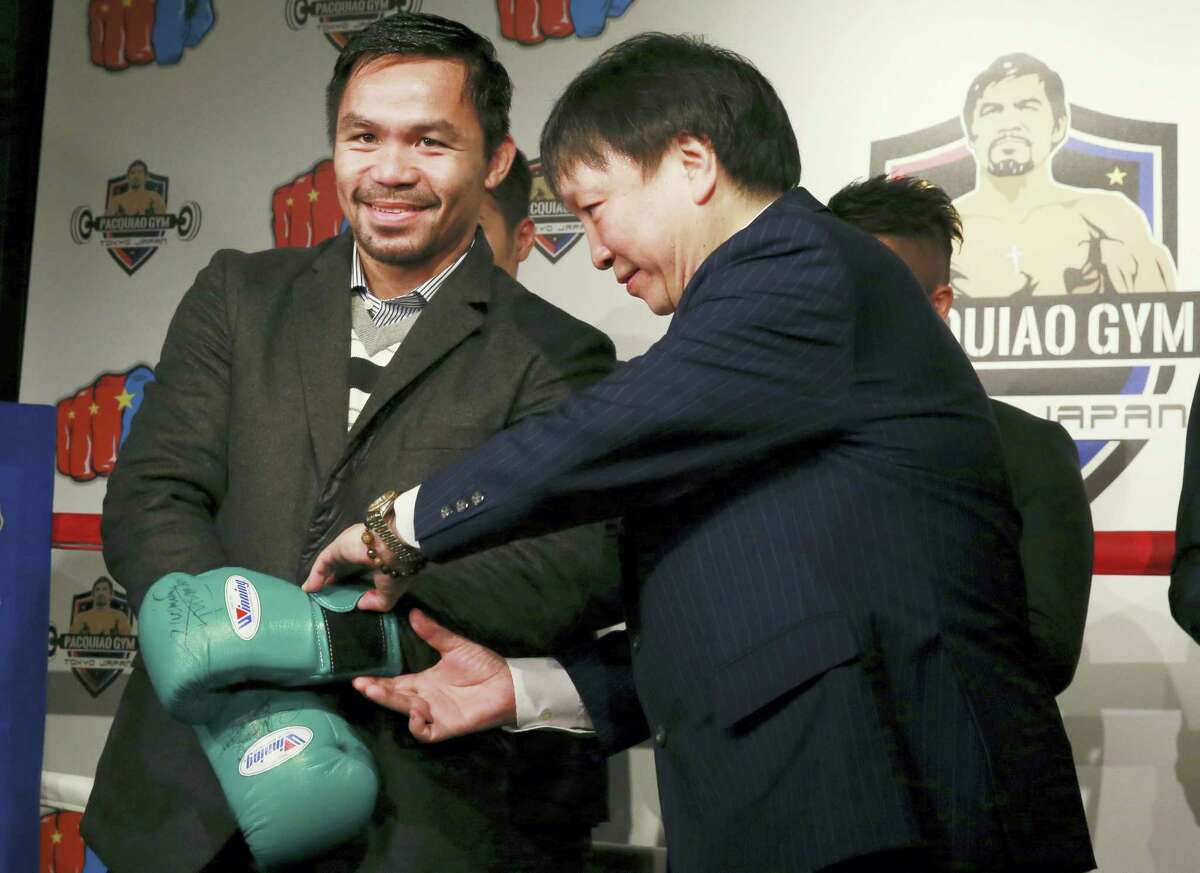 Filipino boxer Manny Pacquiao, left, gets help taking off his gloves during a press conference in Tokyo on Friday.