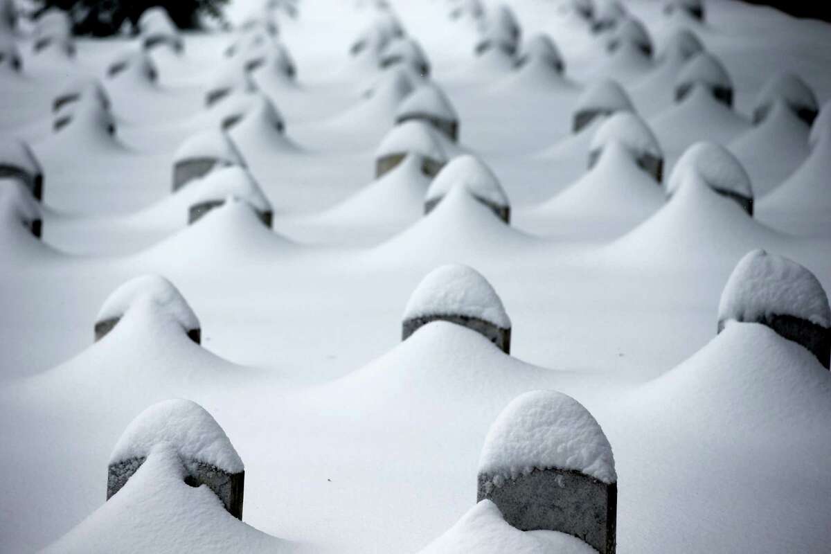 Headstones are nearly covered by snow at Arlington National Cemetery, Saturday, Jan. 23, 2016, in Arlington, Va. A blizzard with hurricane-force winds brought much of the East Coast to a standstill Saturday, dumping as much as 3 feet of snow, stranding tens of thousands of travelers and shutting down the nation’s capital and its largest city.