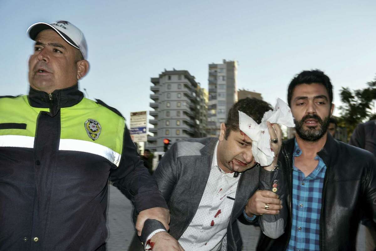 A police officer and a civilian help a wounded person after an explosion that killed people and wounded several others in southern city of Adana, Turkey, Thursday, Nov. 24, 2016. The explosion occurred early Thursday in the car park of a government building, officials said. Turkish authorities have banned distribution of images relating to the Adana explosion within Turkey.