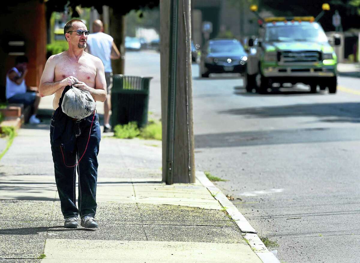 Mike Lucher of New Haven walks on Grand Avenue in New Haven as he combats the heat by going shirtless Friday afternoon.