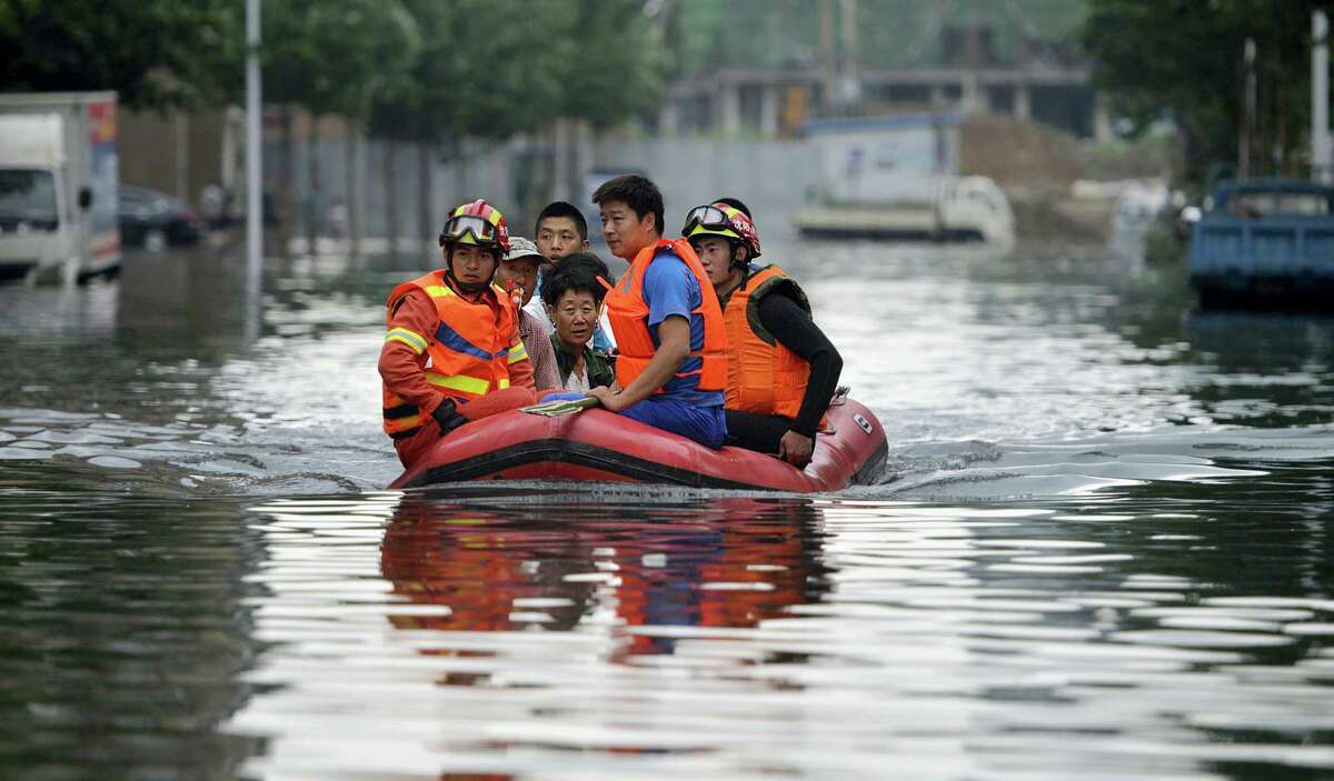 In this Thursday, July 21, 2016, photo, rescuers use a raft to transport people along a flooded street in Shenyang in northeastern China’s Liaoning Province. Dozens of people have been killed and dozens more are missing across China after a round of torrential rains swept through the country earlier this week, flooding streams, triggering landslides and destroying houses.