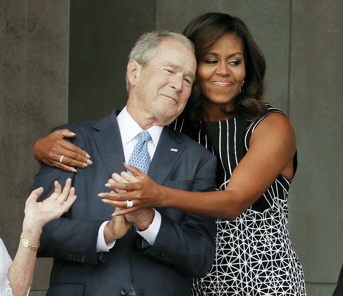 First lady Michelle Obama hugs former President George W. Bush during the dedication ceremony for the Smithsonian Museum of African American History and Culture on the National Mall in Washington, Saturday, Sept. 24, 2016.