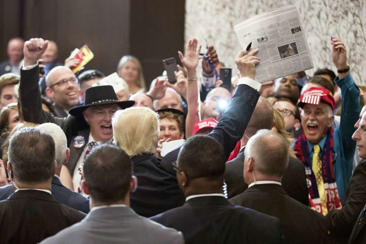 Republican presidential candidate Donald Trump celebrates with crowd members by holding up a copy of the New York Times during a goodbye reception with friends and family following the Republican National Convention Friday in Cleveland.