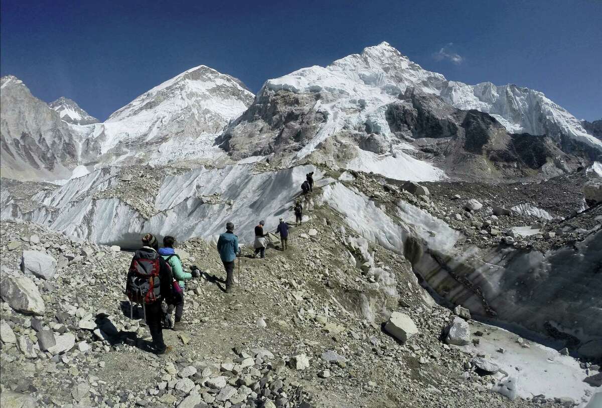 In this Feb. 22, 2016 photo, international trekkers pass through a glacier at the Mount Everest base camp, Nepal. A Nepal official says some 30 climbers have gotten frostbite or become sick on Mount Everest, in addition to two who died in recent days on the world’s highest mountain.