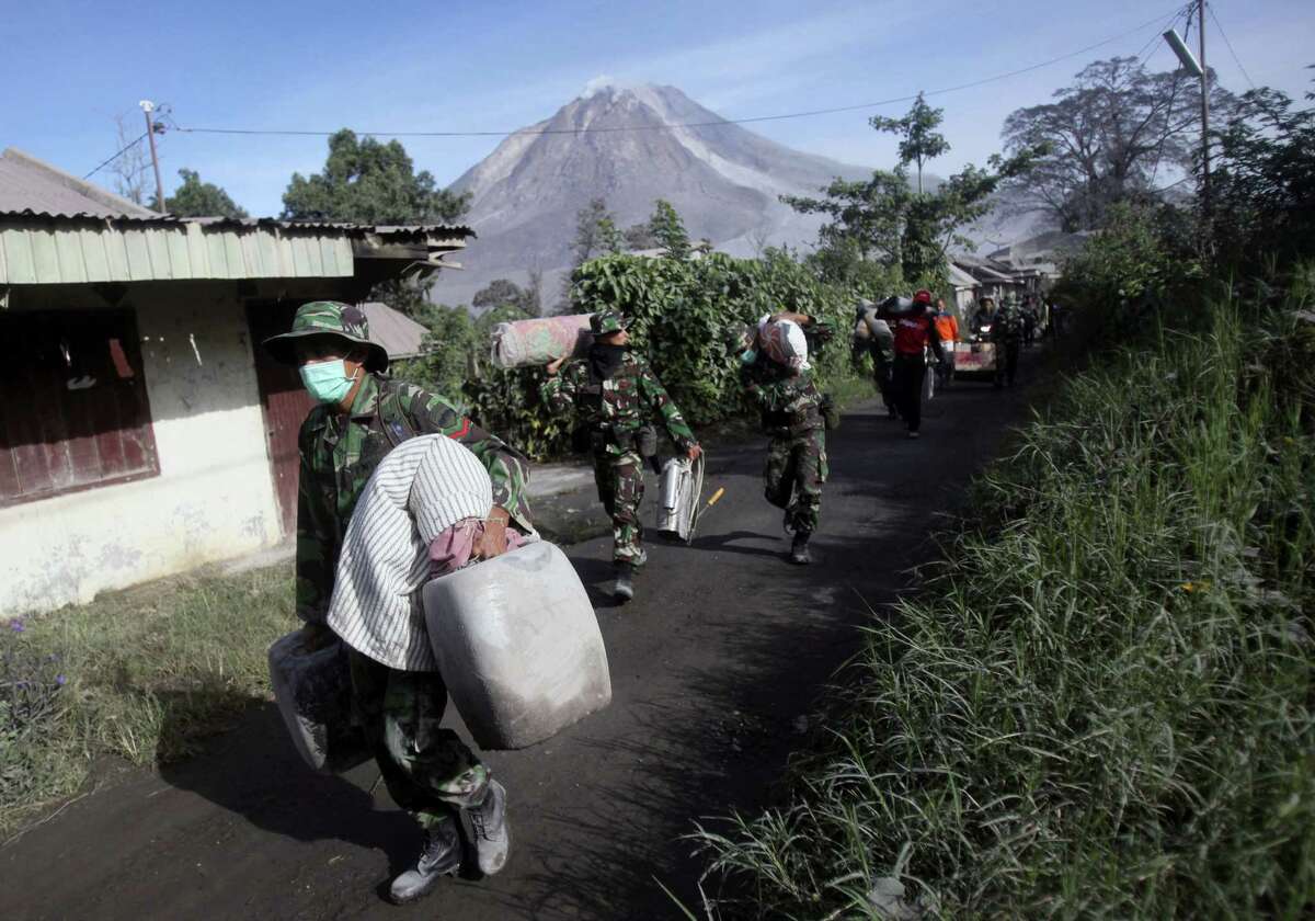 Indonesian soldiers carry people’s belongings during an evacuation following the eruption of Mount Sinabung in Gamber village, North Sumatra, Indonesia on May 22, 2016. The volcano in western Indonesian unleashed hot clouds of ash on Saturday, killing several villagers, officals said.