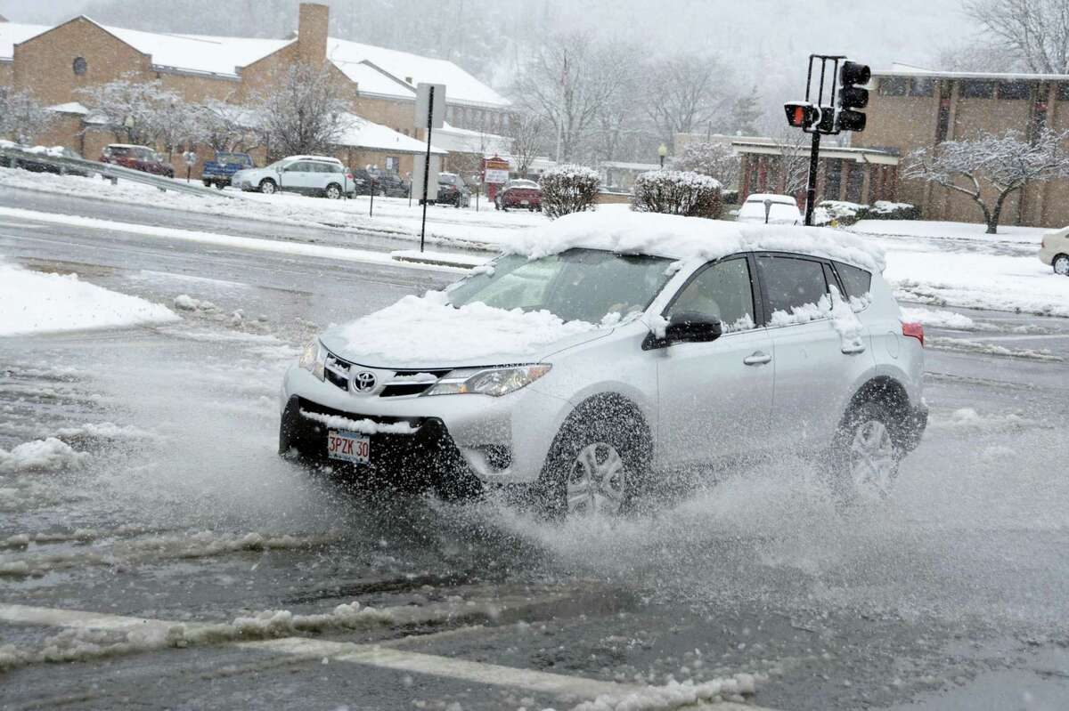 A car splashes through a slush puddle in North Adams, Mass., during a winter storm on Sunday, Nov. 20, 2016.