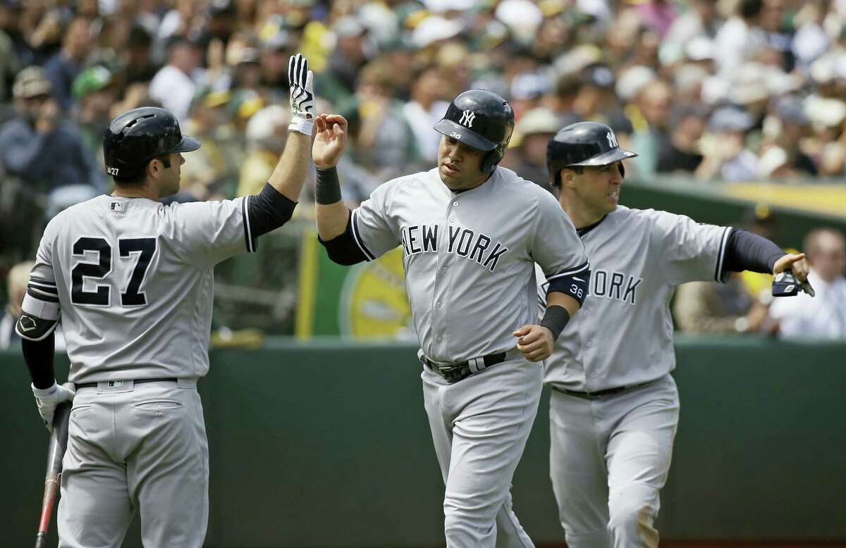 Carlos Beltran, center, and Mark Teixeira, right, are greeted by Austin Romine, left, after scoring in the fourth inning on Sarturday.
