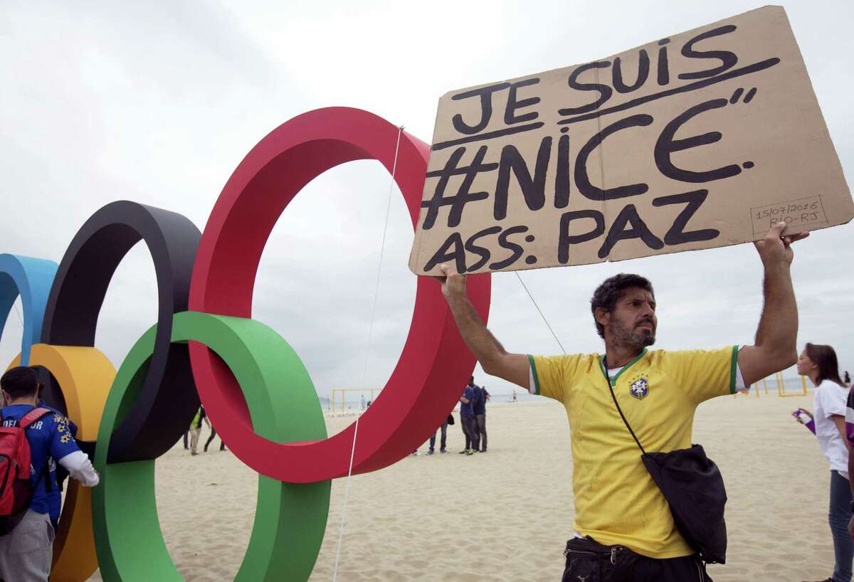 A man holds a sign to show solidarity with Nice during the presentation of Olympic rings made from recycled material, at Copacabana beach in Rio de Janeiro, Brazil. Brazilian police arrested 10 people who allegedly pledged allegiance to the Islamic State group on social media and discussed possible attacks during the Rio de Janeiro Olympics, officials said Thursday.