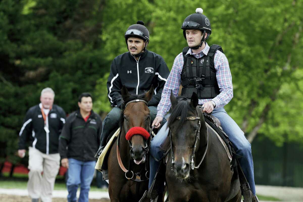 Kentucky Derby winner Nyquist, left, ridden by exercise rider Jonny Garcia, is led back to the barn following a workout by assistant trainer Jack Sisterson, right on Thursday at Pimlico Race Course in Baltimore. The 141st Preakness will be held Saturday.