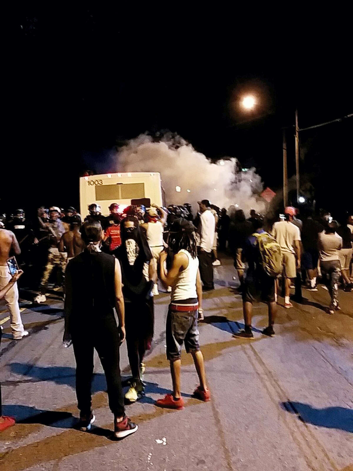 Police fire tear gas into the crowd of protesters on Old Concord Road late Tuesday night, Sept. 20, 2016, in Charlotte, N.C. A black police officer shot an armed black man at an apartment complex Tuesday, authorities said, prompting angry street protests late into the night. The Charlotte-Mecklenburg Police Department tweeted that demonstrators were destroying marked police vehicles and that approximately 12 officers had been injured, including one who was hit in the face with a rock. (Ely Portillo/The Charlotte Observer via AP)