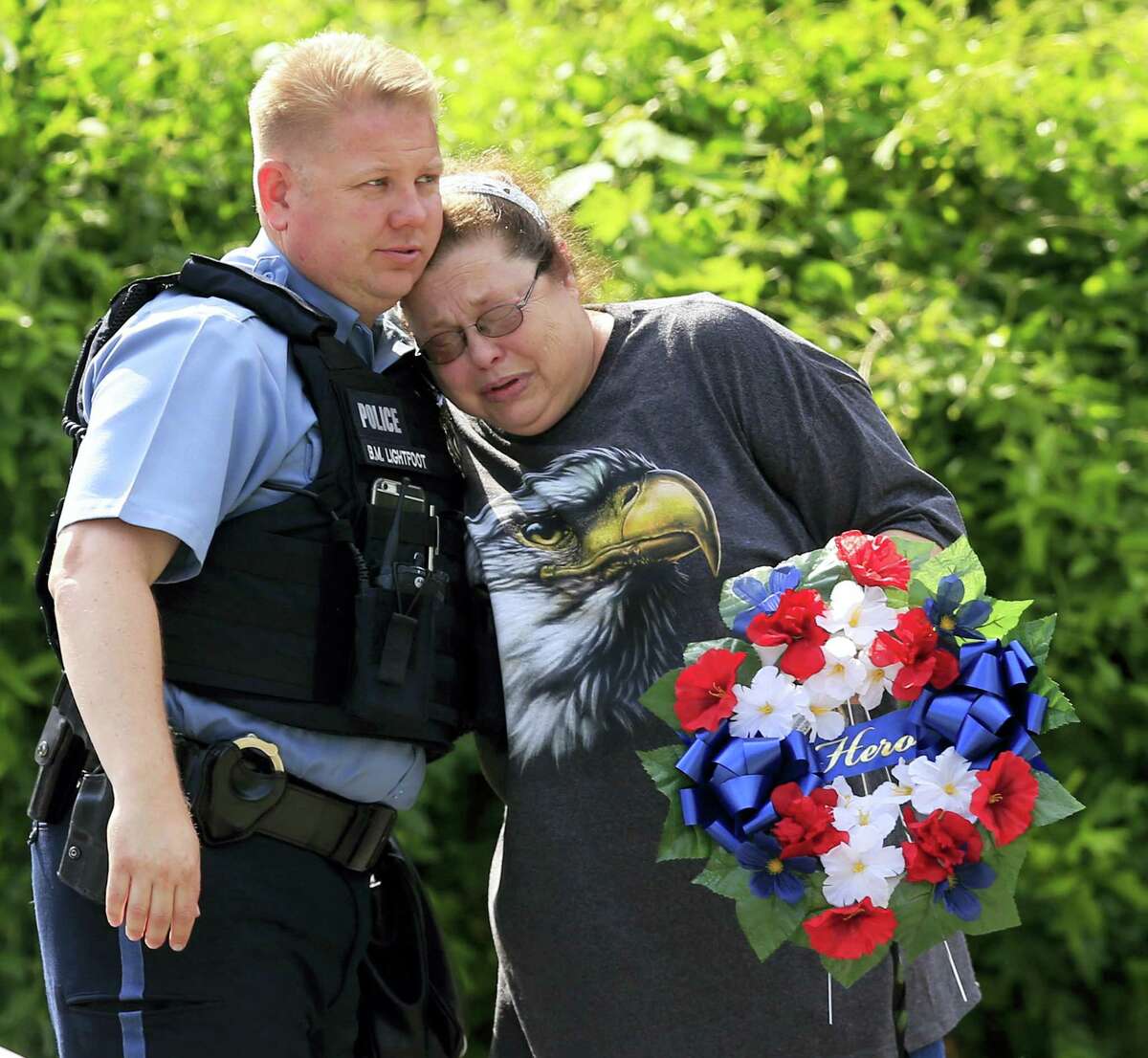 Kansas City, Kan., police officer Brad Lightfoot, left, consuls Susan Goble at the shooting scene of a police officer in Kansas City, Kan. on Tuesday. Goble knows the family of the fallen officer and hoped to place a wreath near the site of the shooting.