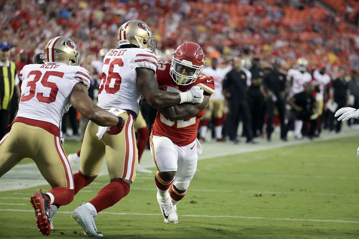 Kansas City Chiefs running back Spencer Ware (32) tries to get past San Francisco 49ers linebacker Reuben Foster (56) and safety Eric Reid (35) during the first half of an NFL preseason football game in Kansas City, Mo., Friday, Aug. 11, 2017. (AP Photo/Charlie Riedel)