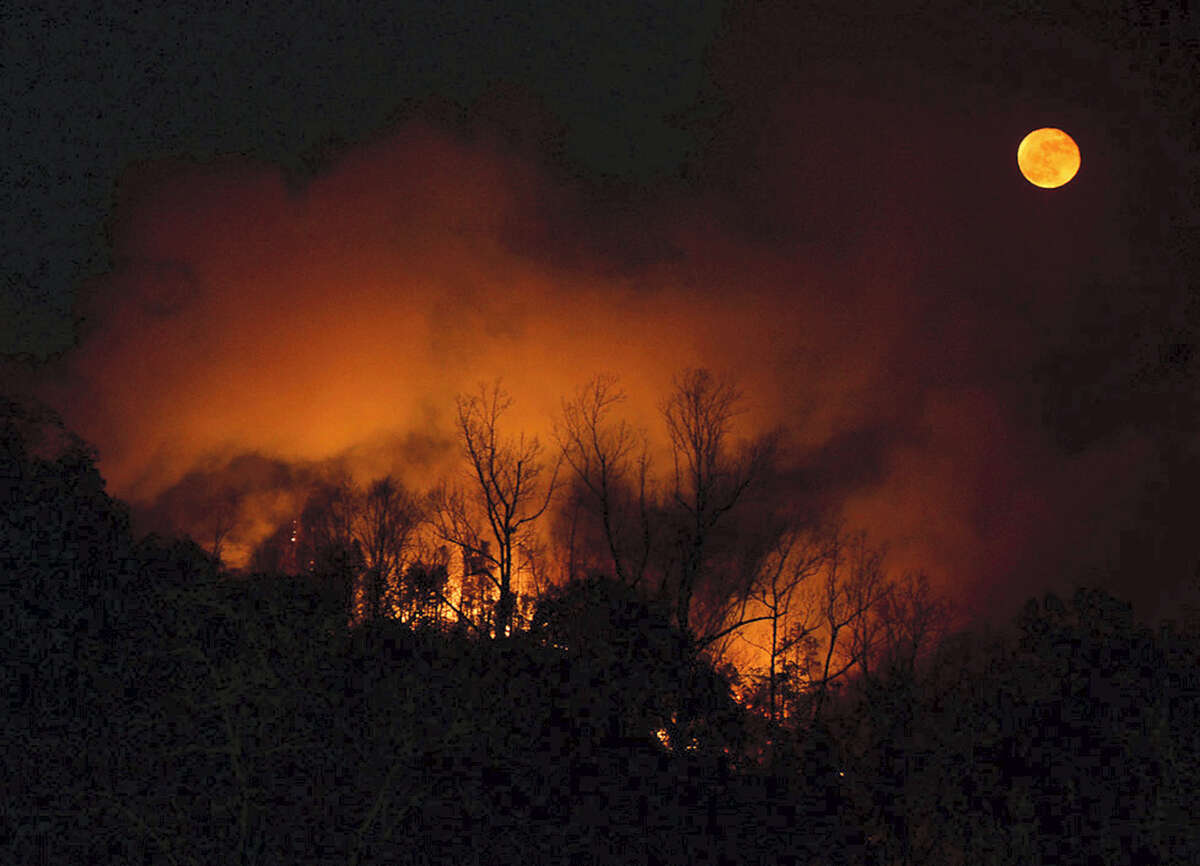 In this Tuesday, Nov. 15, 2016, photo, a wildfire burns as it approaches Bat Cave, N.C. Thick smoke has settled over a wide area of the southern Appalachians, where dozens of uncontrolled wildfires are burning through decades of leaf litter, and people breathe in tiny bits of the forest with every gulp of air.