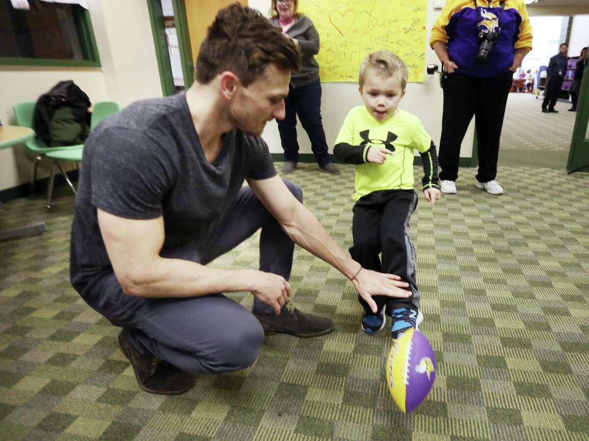 Max Birdwell, 4, kicks a football from the hold of Vikings kicker Blair Walsh during a visit to Northpoint Elementary School, Thursday in Blaine, Minn. First graders at the school wrote letters of encouragement to Walsh after he missed a potentially game-winning field goal in last Sunday’s NFL football playoff game against the Seahawks.