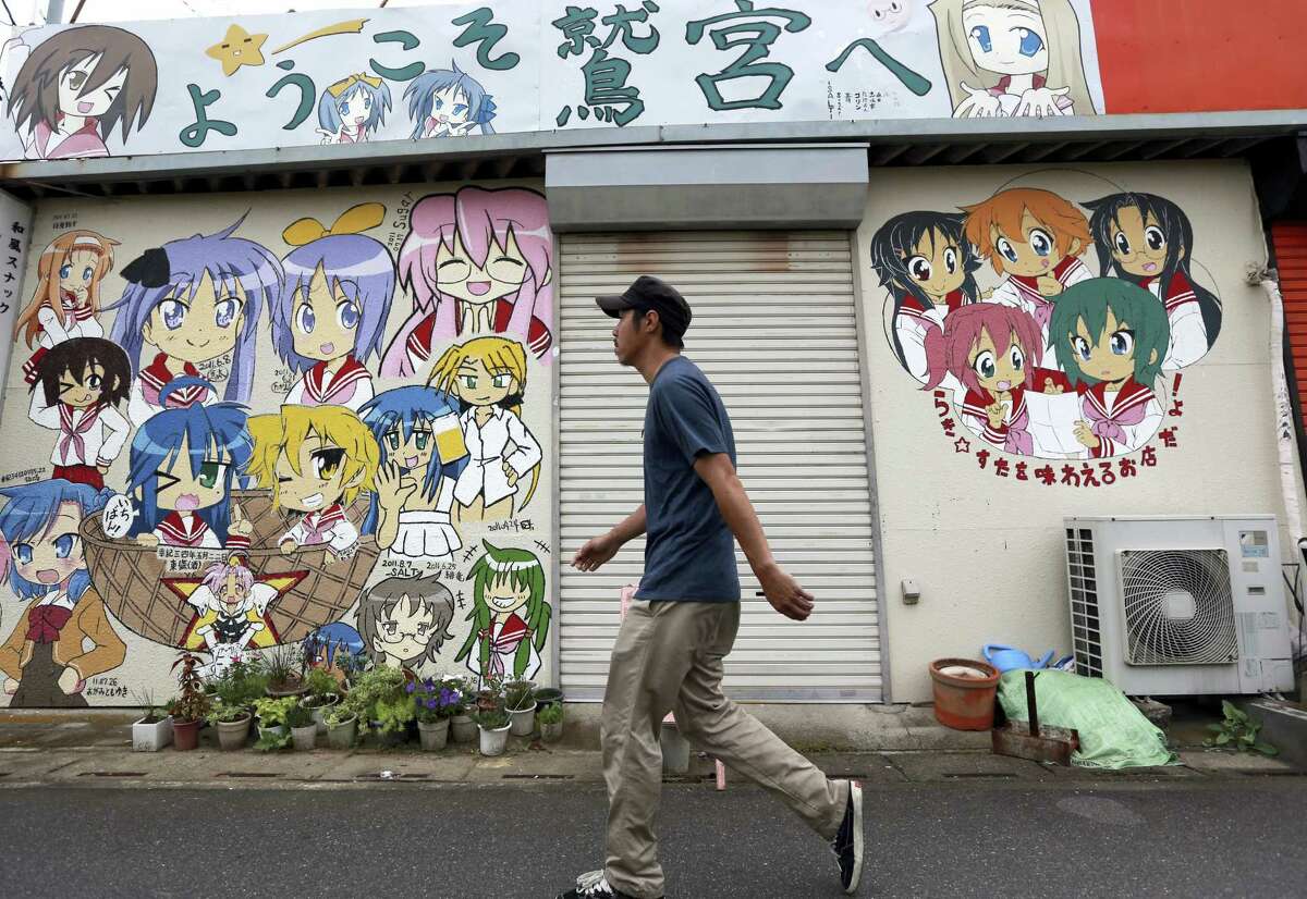 A man walks by an eatery with its facade painted with letters that read “Welcome to Washinomiya” and the characters of a TV animation series “Lucky Star” or “Raki Sta” near Washinomiya Jinja shrine in Kuki, Saitama prefecture, north of Tokyo.