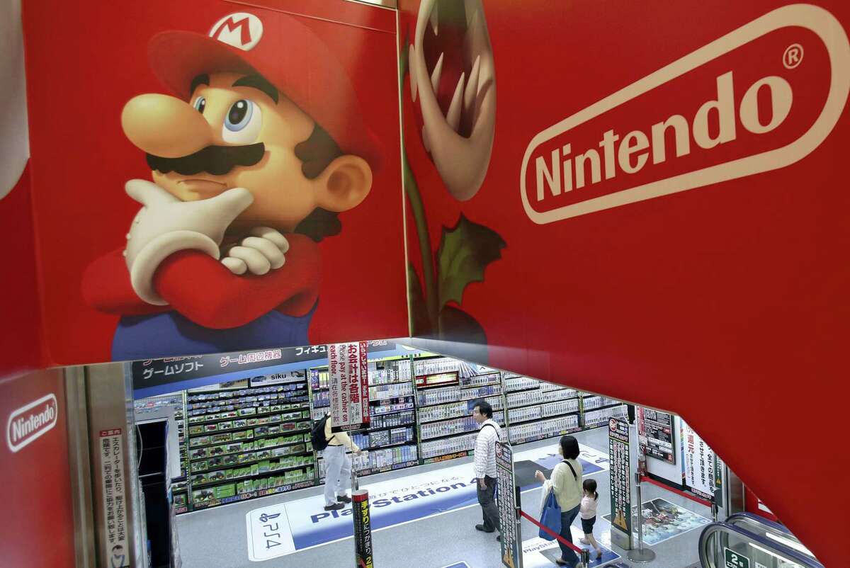 Shoppers walk under the logo of Nintendo and Super Mario characters at an electronics store in Tokyo.