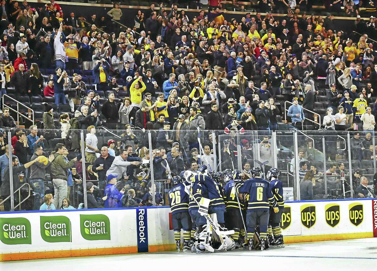 Members of the Quinnipiac hockey team celebrate Derek Smith’s overtime goal that gave the Bobcats a 5-4 win over Harvard at the Madison Square Garden in New York on Saturday.