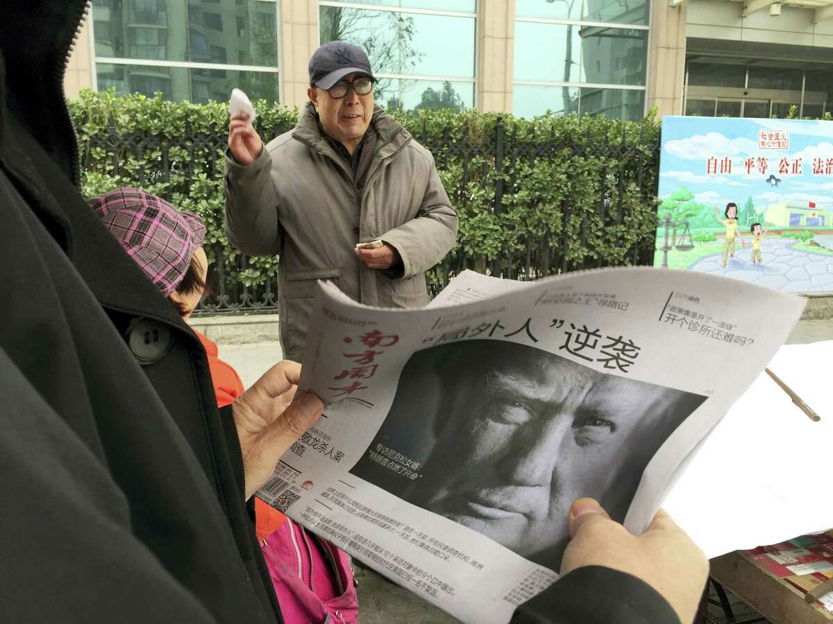 A Chinese man holds up a Chinese newspaper with the front page photo of U.S. President-elect Donald Trump and the headline “Outsider counter attack” at a newsstand in Beijing, China, Thursday.