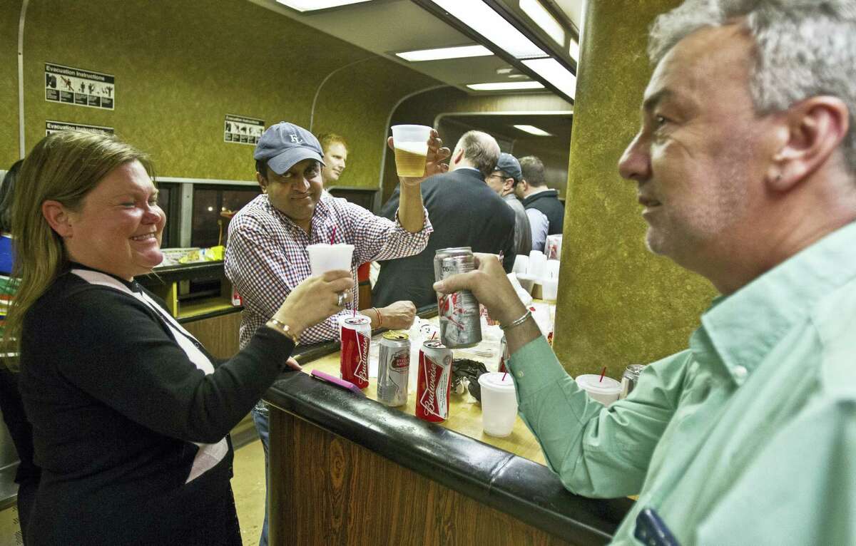 In this May 8, 2014, photo, Nan Buziak Lexow, left, Srikanth Reddy, center, and Mark DeMonte, right, raise a toast while riding the bar car on the 7:07 p.m. train from Grand Central Terminal in New York to New Haven, Conn. The bar cars were retired from Metro-North’s New Haven Line after the afternoon rush hour.