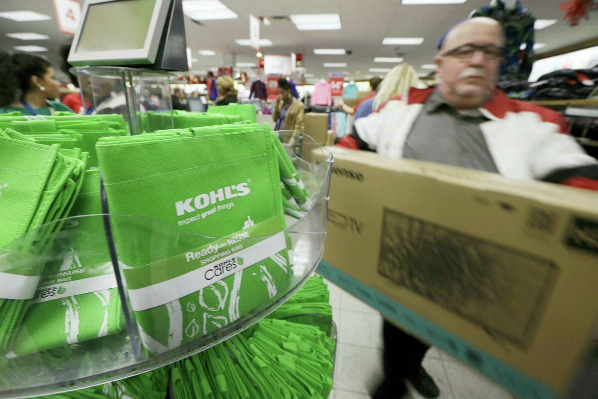 A customer carries a television from the checkout at a Kohl’s department store in Sherwood, Ark.