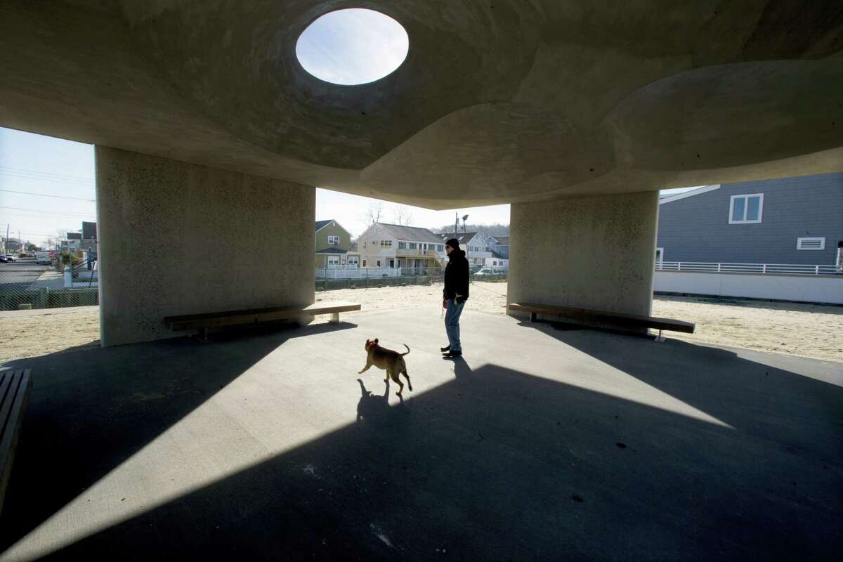 A man and his dog stand in a large concrete structure on the beach Wednesday, Jan. 6, 2016, in Highlands, N.J. The borough is demanding that a trade group remove the monument to survivors of Superstorm Sandy. A Highlands attorney sent a letter to the Tilt-Up Concrete Association Monday, asking the group to remove the more than 1,000-square-foot monument from the beach. The monument is dubbed “Shorehenge.”