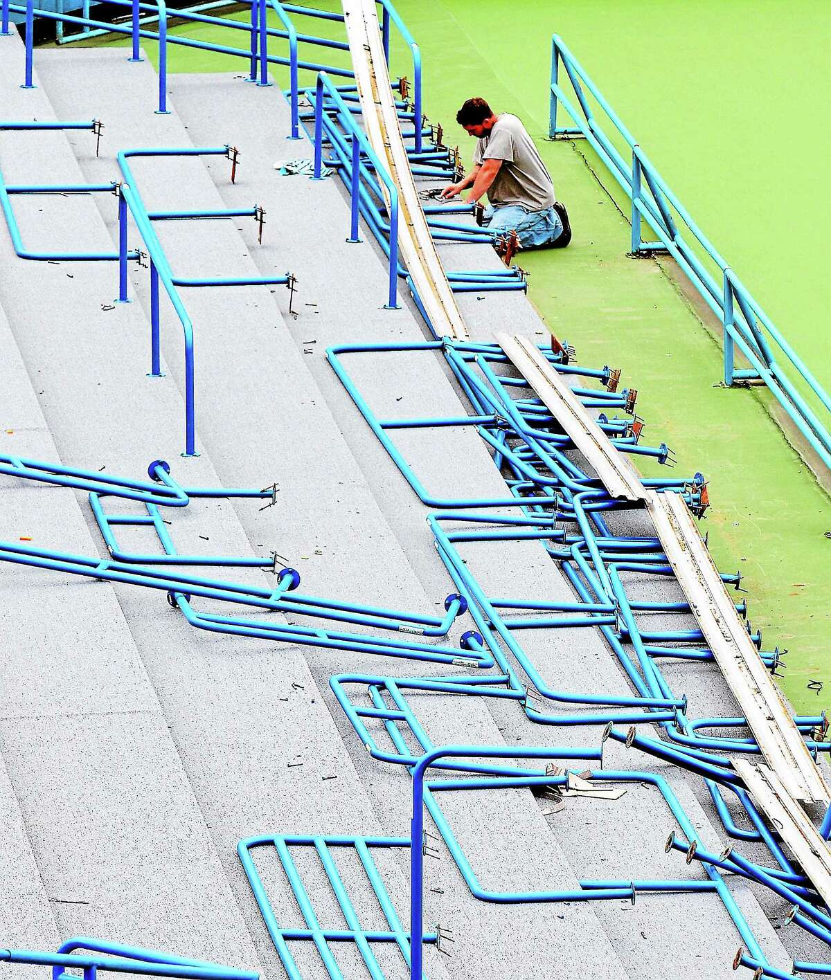 An installer works on railings in the Connecticut Tennis Center stadium court.
