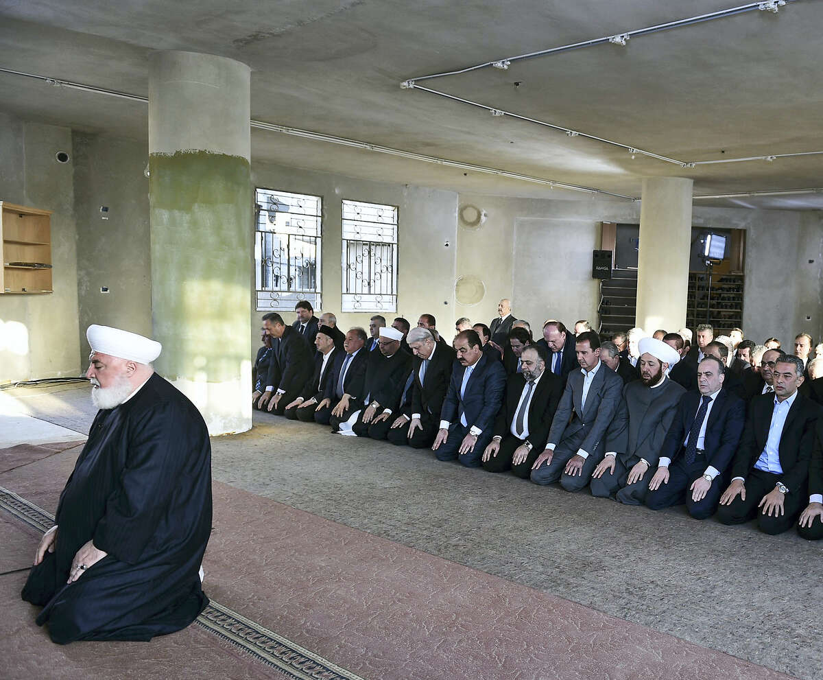 In this photo released on the official Facebook page of the Syrian Presidency, Syrian President Bashar Assad, fourth right, prays at the dawn Eid al-Adha prayers at the Saad ibn Muaaz Mosque in Daraya, a blockaded Damascus suburb, Syria on Sept. 12, 2016.