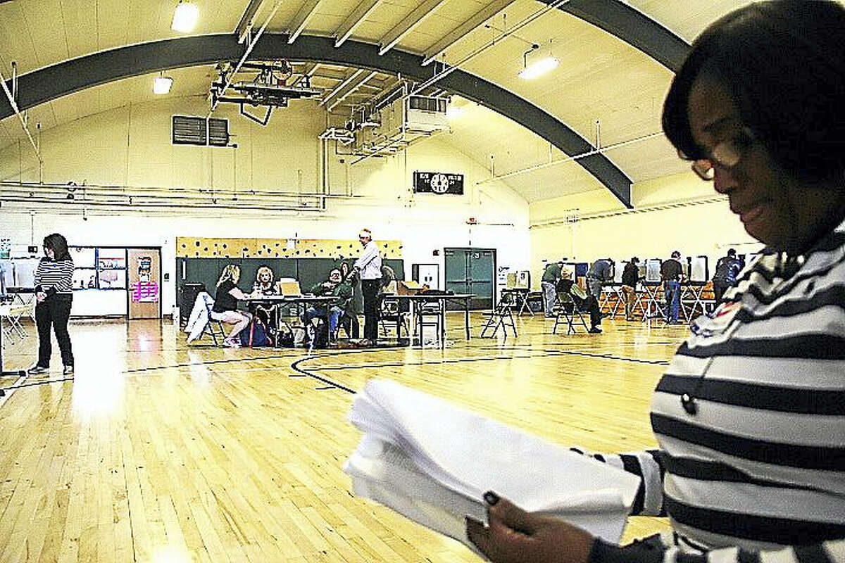 A poll worker directs Middletown voters to sign-in tables at Woodrow Wilson Middle School.
