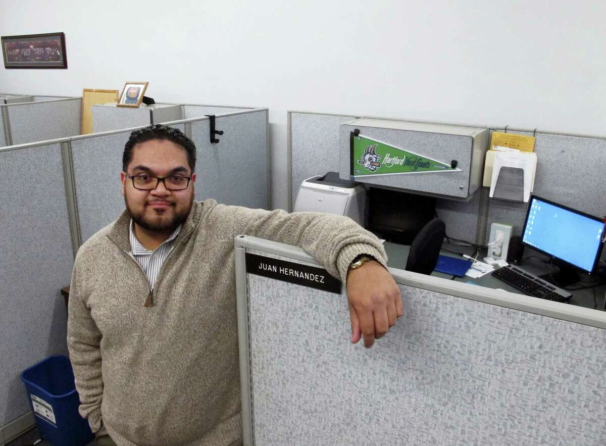 Juan Hernandez, an aide to a Hartford City Council member, poses at his work cubicle in Hartford City Hall on March 7, 2016, in Hartford.