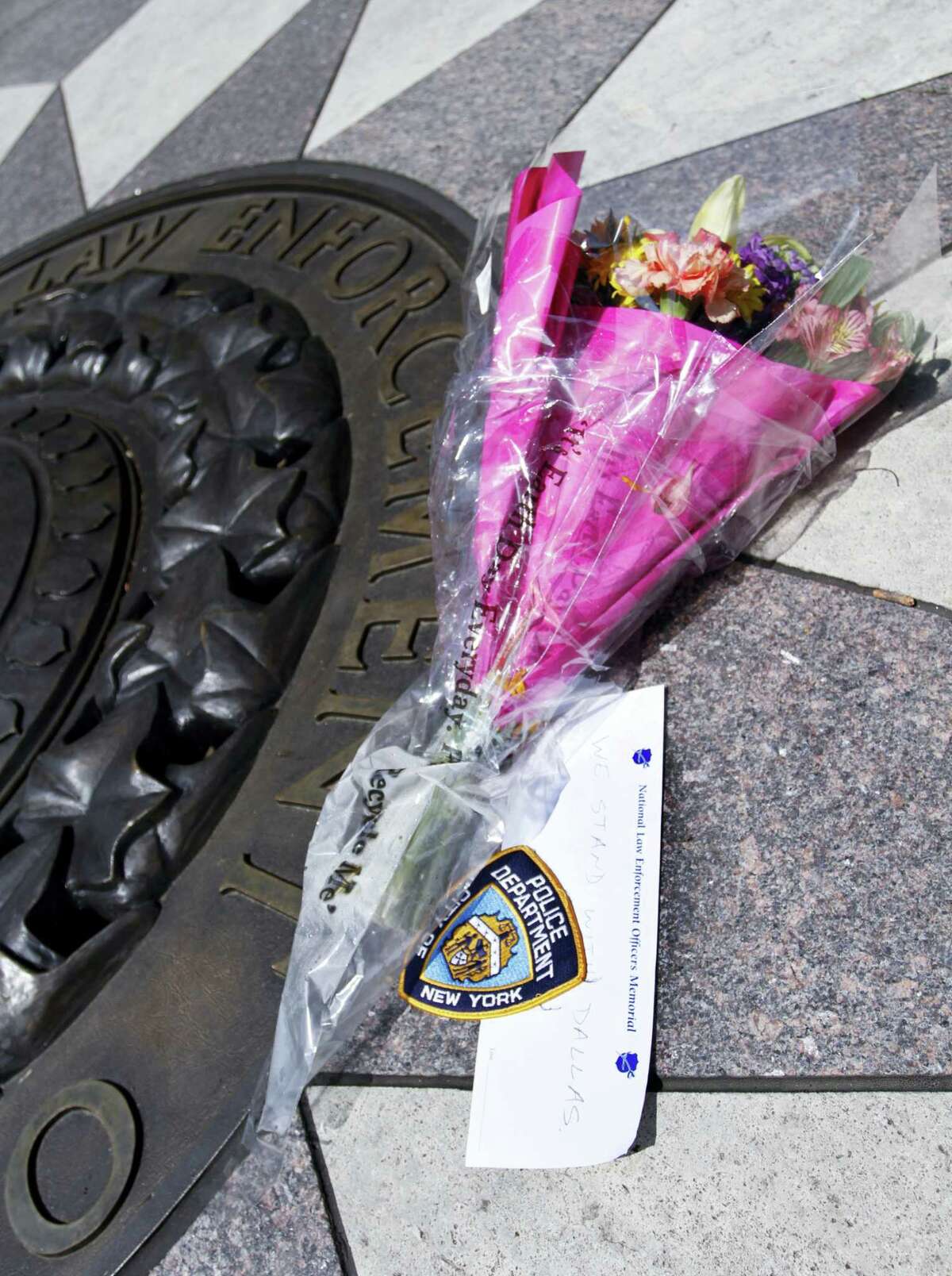 A bouquet of flowers with a note of support for the Dallas Police Department lies on the bronze medallion at the National Law Enforcement Officers Memorial in Washington Friday.