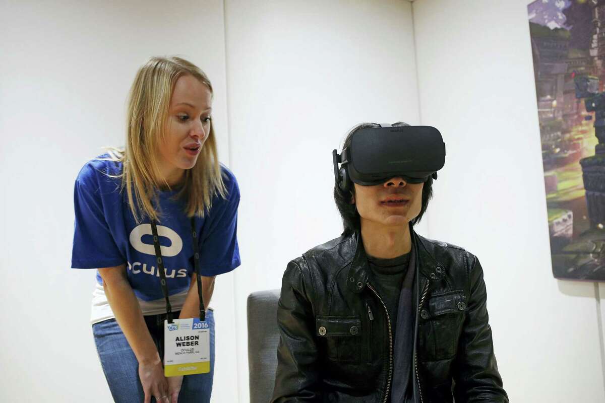 Alison Weber, left, instructs Peijun Guo on using the Oculus Rift VR headset at the Oculus booth at CES International in Las Vegas.