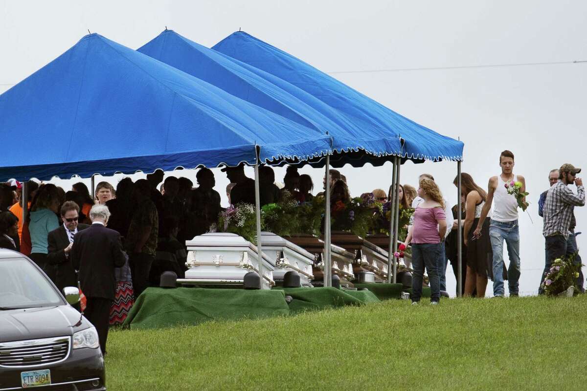 Mourners gather around row of caskets at Scioto Burial Park during funeral services for six of the eight murder victims from Pike County, Tuesday, May 3, 2016, in McDermott, Ohio. Seven adults and a 16-year-old boy from the Rhoden family were found dead April 22 at four properties scattered across a few miles of countryside near Piketon, about 80 miles east of Cincinnati.