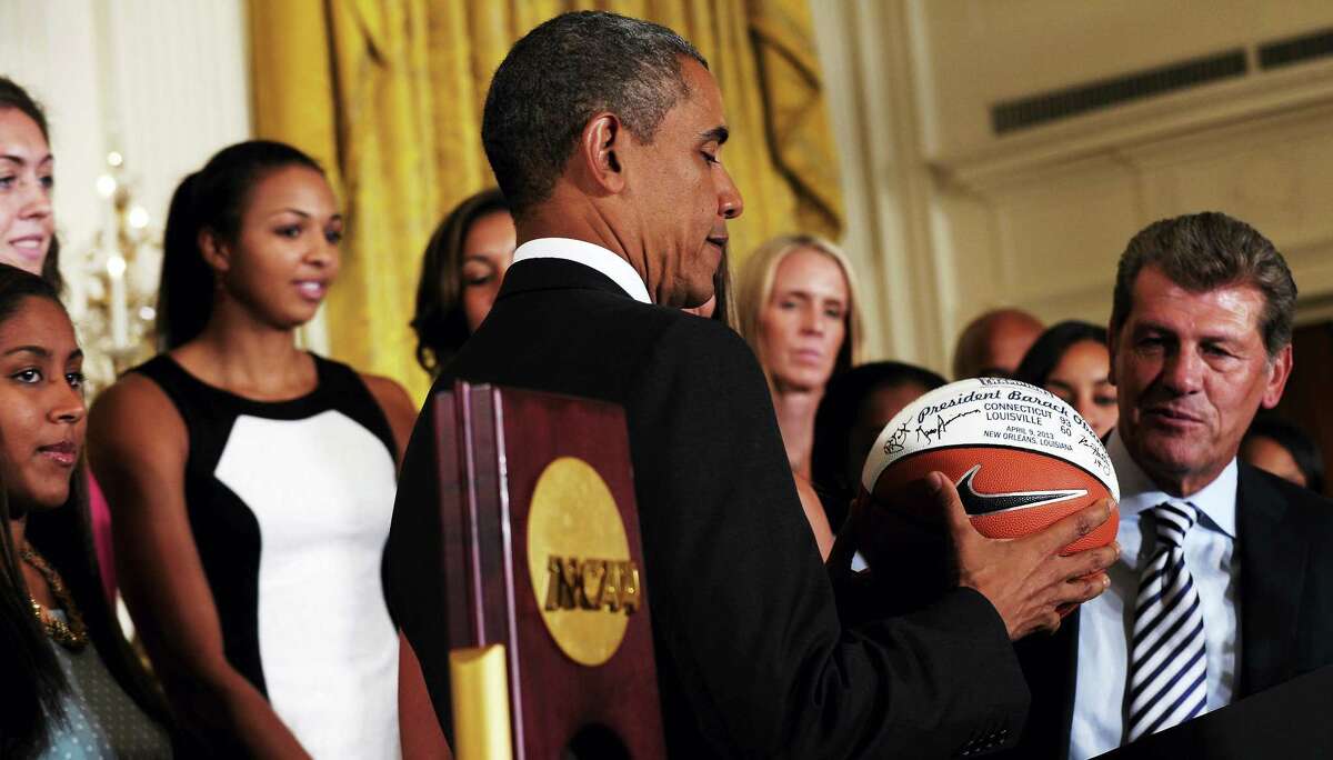 President Barack Obama looks at the basketball that he was given during a ceremony to honor the 2013 NCAA Womenï¿½s Basketball Champion team, the University of Connecticut Huskies, Wednesday, July 31, 2013, in the East Room of the White House in Washington, Wednesday, July 31, 2013. UConn head basketball coach Geno Auriemma watches at right. (AP Photo/Susan Walsh)