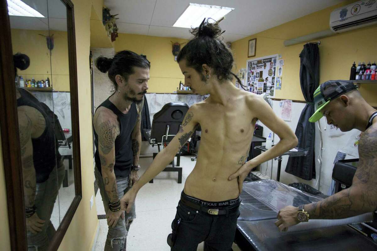 Customer Adrian Alfaro, center, is flanked by tattoo artist Angel Fernando, and Leo Canosa, as they ready for an ink session at La Marca or The Brand tattoo parlor in Havana, Cuba. The studio is an example of Cuba’s new acceptance of tattooing. The shop opened a year ago on one of Old Havana’s busiest streets and has inked hundreds of tattoos for a mix of Cuban and foreign clients.