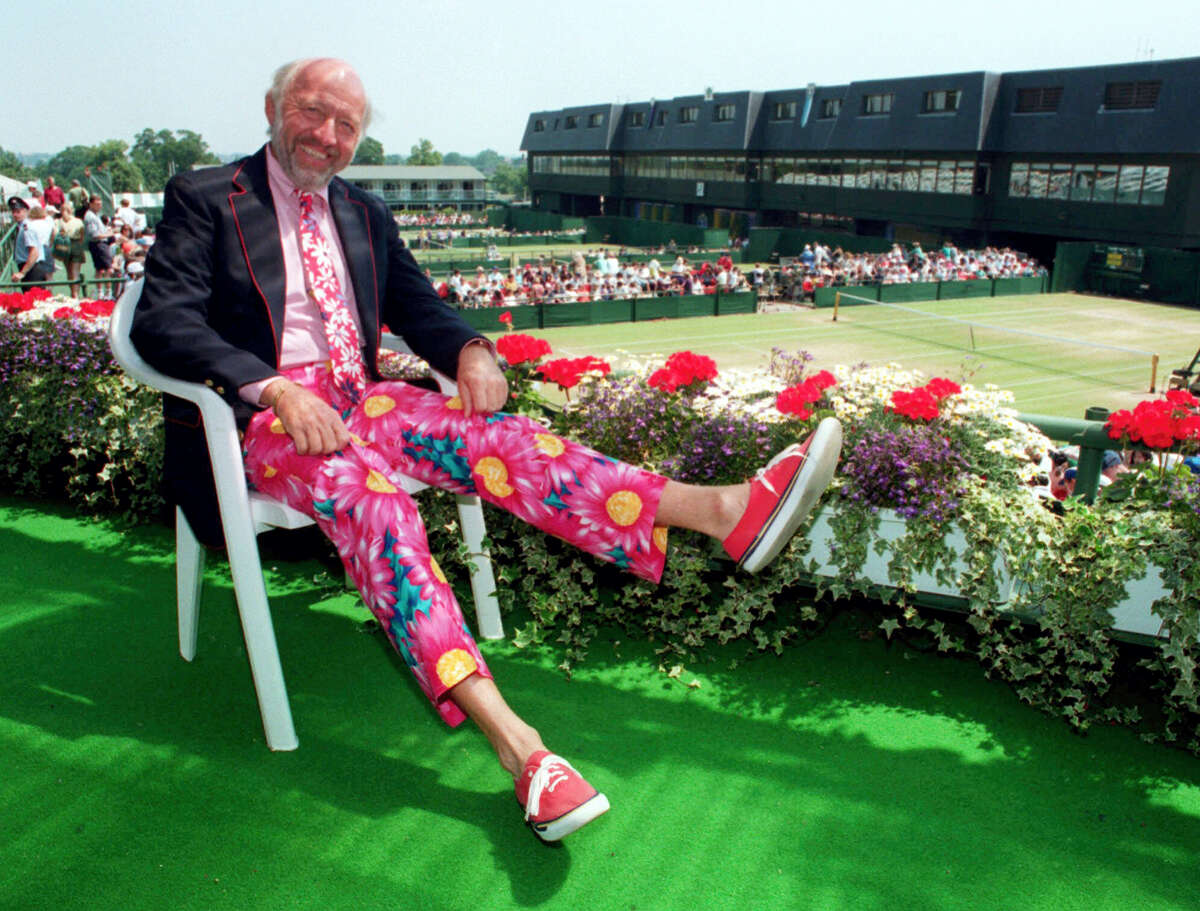 In this 1993 file photo, NBC tennis commentator Bud Collins displays a pair of brightly-colored trousers as he sits overlooking the outside courts at Wimbledon, England. Collins, the tennis historian and American voice of the sport in print and on TV for decades, died Friday. He was 86.