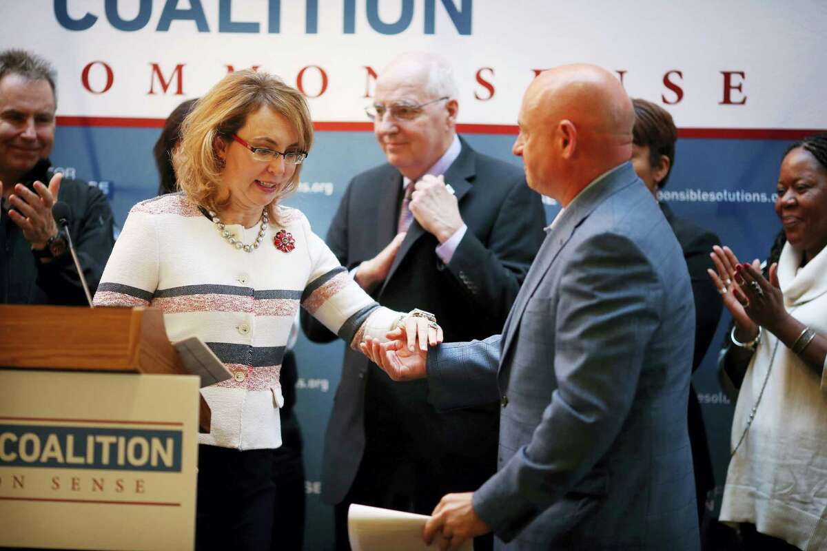 Gabrielle Giffords is helped off the stage by her husband Mark Kelly after speaking during a news conference at Augsburg College in Minneapolis about gun control.