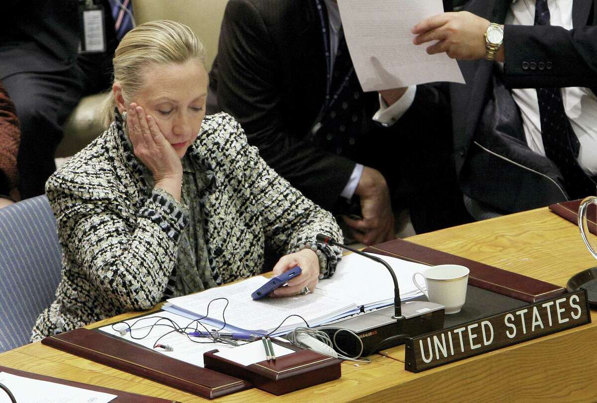 In this March 12, 2012, file photo, then-Secretary of State Hillary Rodham Clinton checks her mobile phone after her address to the Security Council at United Nations headquarters. An impromptu meeting between Bill Clinton and the nation’s top cop could further undermine Hillary Clinton’Äôs efforts to convince voters to place their trust in her, highlighting perhaps her biggest vulnerability.