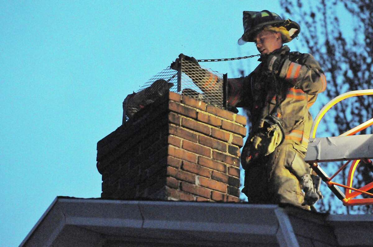 A South Fire District firefighter uses a chain to loosen debris after a chimney fire in Middletown.