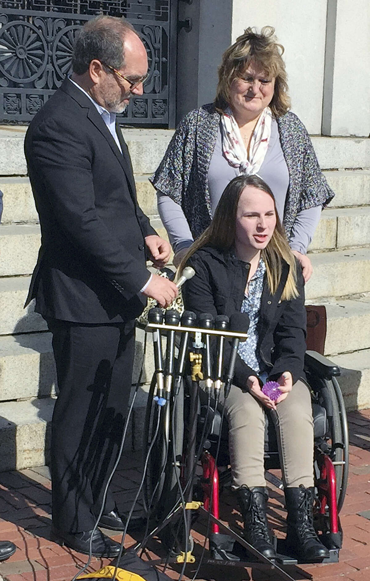 Justina Pelletier, seated, speaks to media alongside the Rev. Patrick Mahoney, left, and her mother Linda Pelletier on Thursday, Feb. 25, 2016, outside the Statehouse in Boston. The Pelletier’s filed a lawsuit against Children’s Hospital in Boston over a medically-related custody dispute. The case hinged on dueling diagnoses of Justina’s condition.