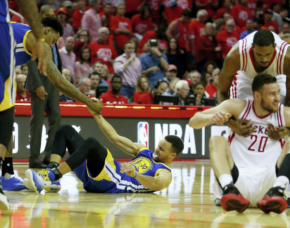 In this April 24, 2016 photo, Golden State Warriors guard Stephen Curry (30) is helped up after being injured on the final play during the first half of Game 4 in the first round of the NBA playoff series against the Houston Rockets, in Houston.