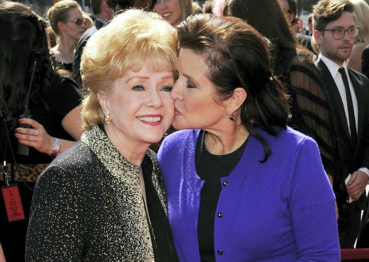 In this Sept. 10, 2011, file photo, Carrie Fisher kisses her mother, Debbie Reynolds, as they arrive at the Primetime Creative Arts Emmy Awards in Los Angeles. On Friday, Dec. 30, 2016, Reynolds’ son, Todd Fisher, says his mother and sister will have a joint funeral and will be buried together at Forest Lawn Memorial Park cemetery in Los Angeles.