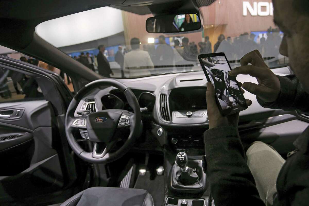 A man takes photographs with a phone inside the new Ford Kuga SUV car, which features its latest connectivity and driver-assisted technology, during the Mobile World Congress Wireless show, the world’s largest mobile phone trade show, in Barcelona, Spain on Feb. 22, 2016.