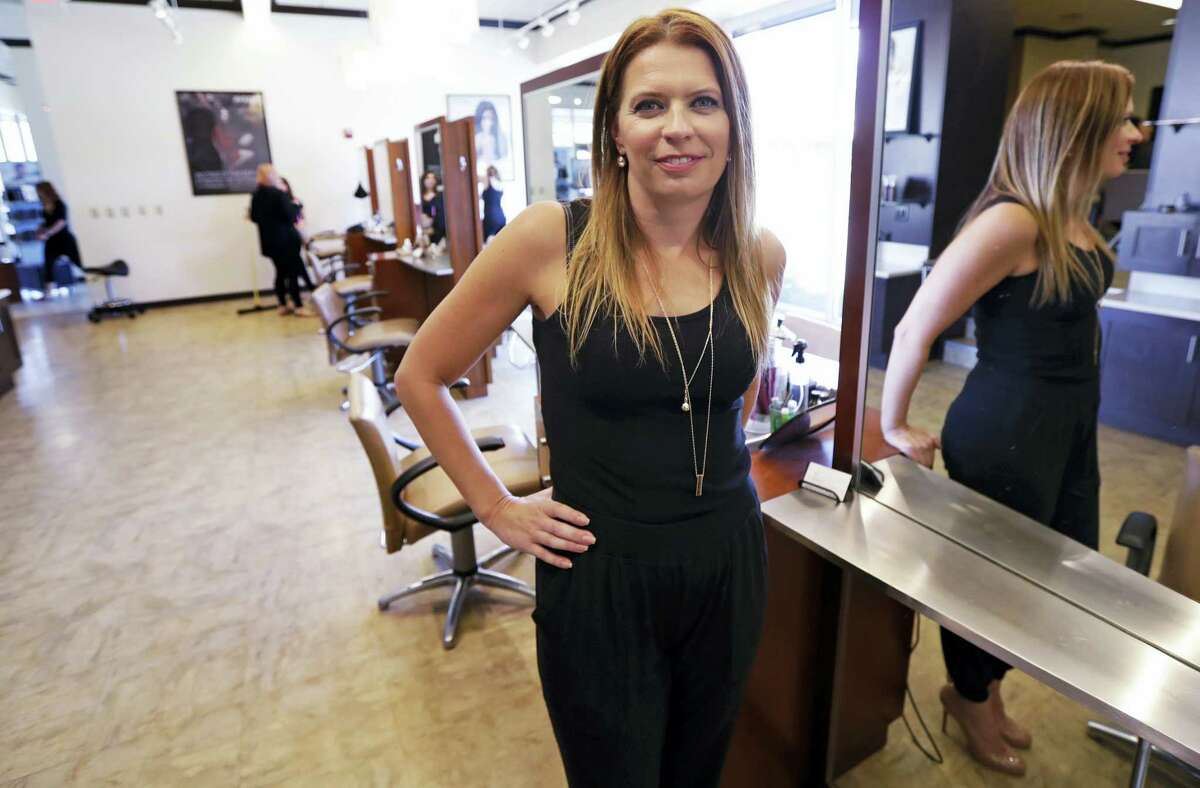 In this Aug. 23, 2016 photo, Christine Perkins, who owns Pyara Spa and Salons at two locations in the Boston area, poses at a stylist station at her salon in Burlington, Mass. Perkins struggles to find candidates to style hair, do manicures and give massages, in part because some beauty schools in the region have closed.