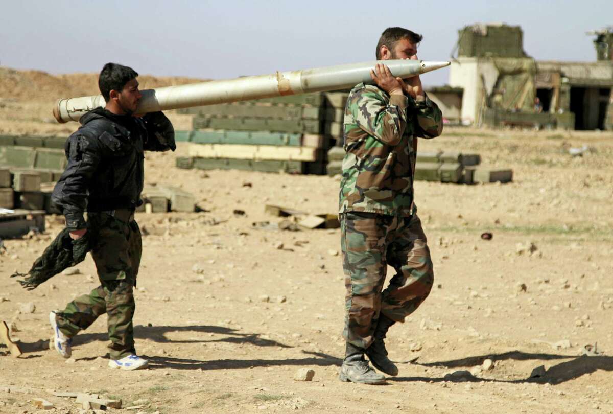 In this photo taken on Feb. 17, 2016, soldiers from the Syrian army carry a rocket to fire at Islamic State group positions in the province of Raqqa, Syria. In recent weeks, Syrian government forces captured dozens of villages and towns across the country.